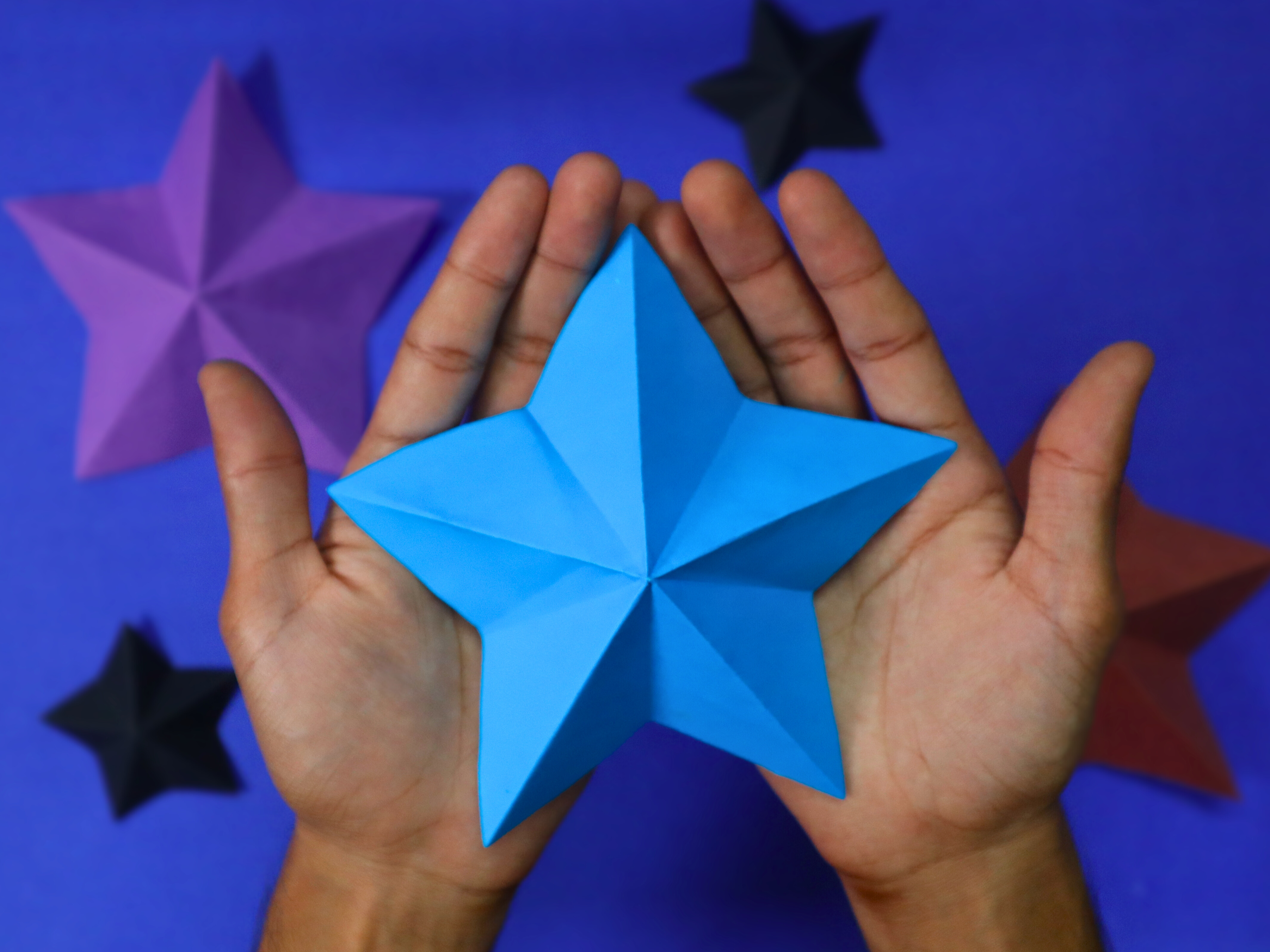 Hands holding a beautifully crafted 3D paper star, linking to the Kami DIY YouTube channel